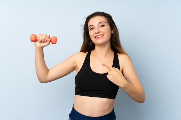 Mujer joven deporte con pesas sobre pared azul aislado y apuntando