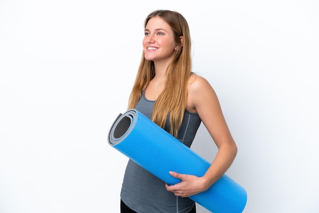 Mujer joven deporte que va a clases de yoga mientras sostiene una estera mirando de lado