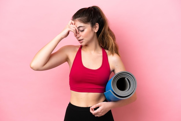 Mujer joven deporte que va a clases de yoga mientras sostiene una estera riendo