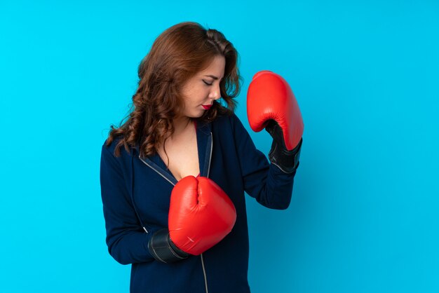 Mujer joven del deporte sobre la pared azul aislada