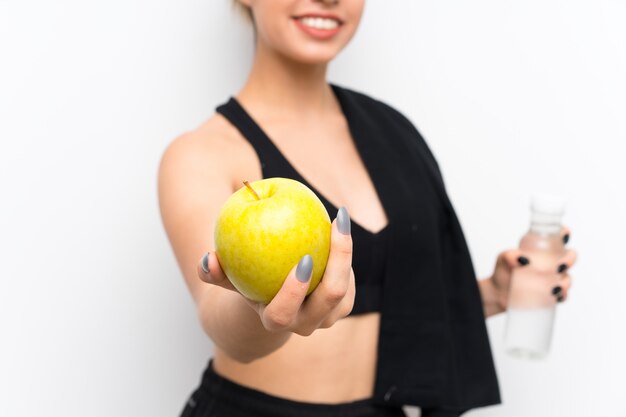 Mujer joven deporte sobre pared blanca con una manzana