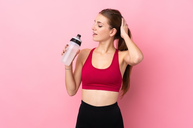 Mujer joven deporte sobre pared rosa aislado con botella de agua deportiva