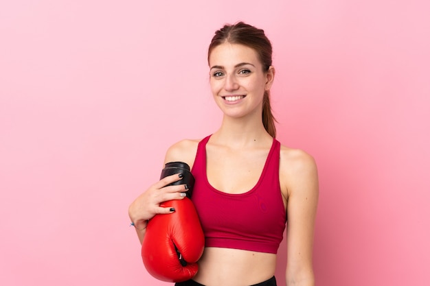 Mujer joven del deporte sobre la pared rosada aislada con los guantes de boxeo