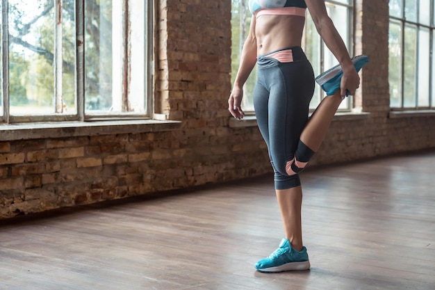 Mujer joven deportiva entrenador de fitness calentar la pierna estirada