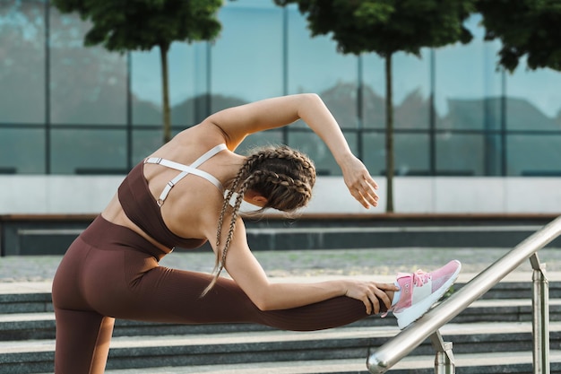 Mujer joven y deportiva está estirando durante el entrenamiento de fitness al aire libre