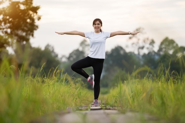 Mujer joven deportiva haciendo ejercicios en el camino de madera en el campo