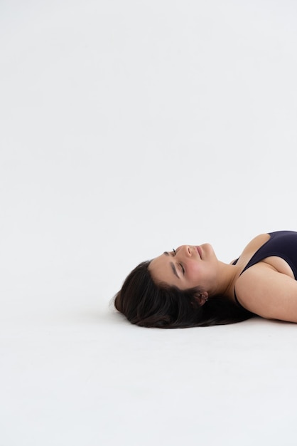 Mujer joven deportiva haciendo práctica de yoga relajante aislado sobre fondo blanco.