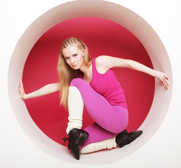 Mujer joven deportiva posando en círculo rosa