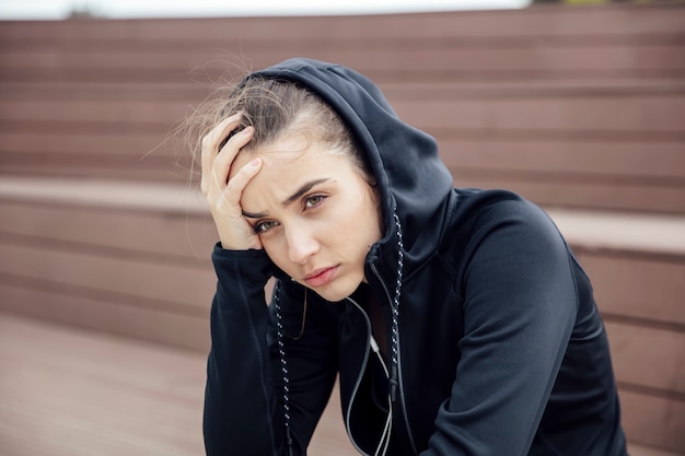 Mujer joven deportiva triste y frustrada que se sienta al aire libre