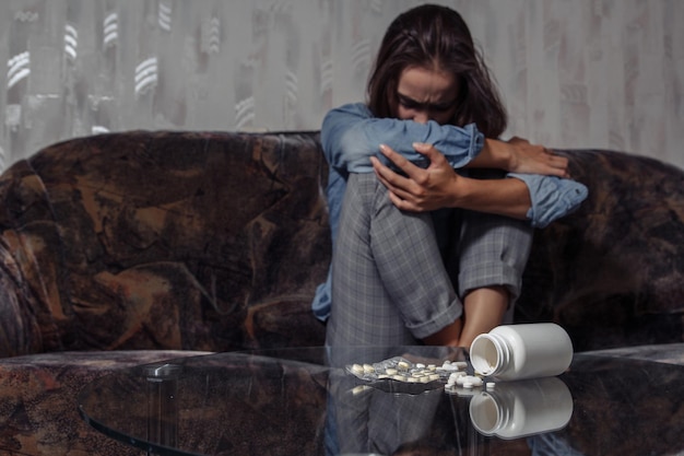 Foto mujer joven en depresión y desesperación pensando en suicidio químico y sobredosis de pastillas