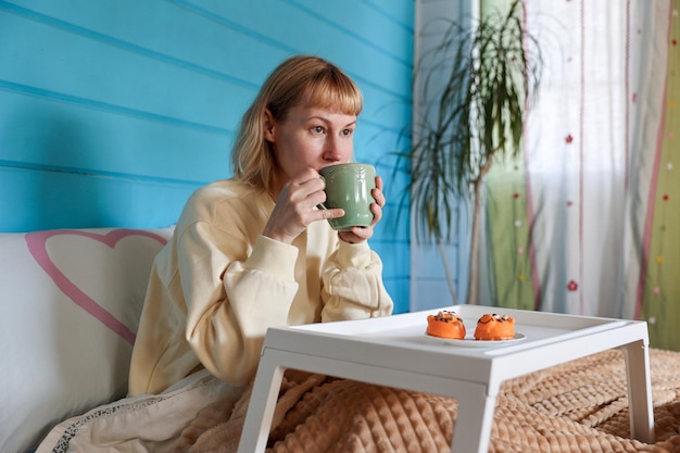 La mujer joven desayuna en la cama