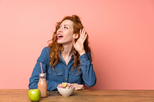 Mujer joven con desayuno sobre rosa aislado