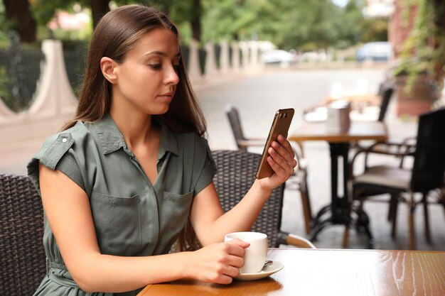 Mujer joven desbloqueando teléfono inteligente con escáner facial en un café al aire libre Verificación biométrica