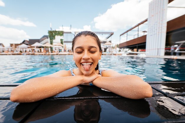 Mujer joven descansando en el borde de la piscina