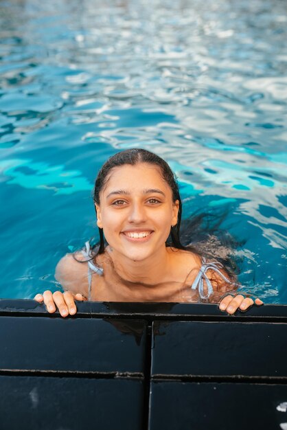 Mujer joven descansando en el borde de la piscina