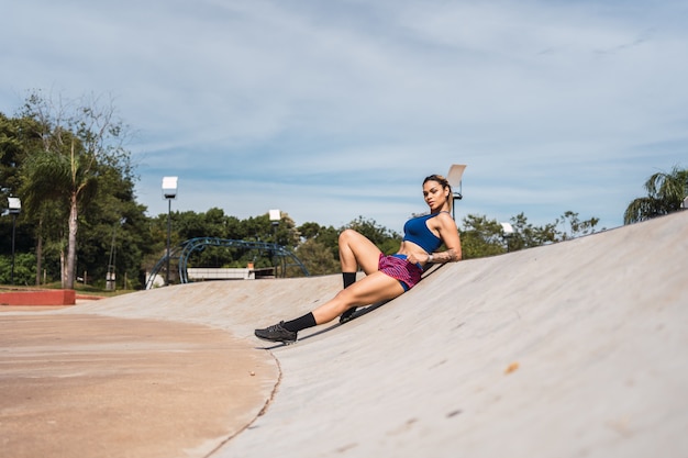 Una mujer joven descansando después de hacer ejercicio en un parque urbano.