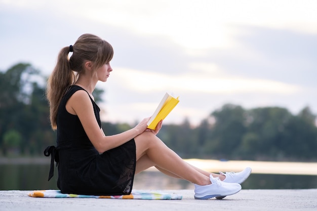 Mujer joven descansando en el parque de verano leyendo un libro Educación y concepto de estudio