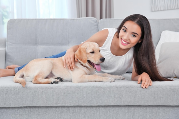 Mujer joven descansando con un perro perdiguero amarillo en casa