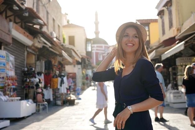 Mujer joven descubriendo la ciudad de Rodas al atardecer con la Mezquita de Suleiman en el fondo Grecia