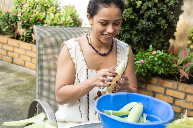 Mujer joven desgranando maíz para crear una comida típica