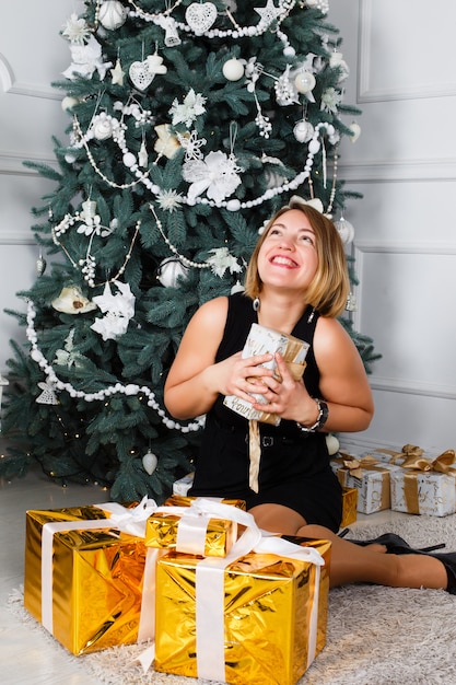 Mujer joven desordenar la cinta en los regalos de Navidad.