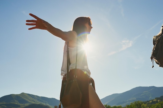 Mujer joven despreocupada balanceándose y caminando durante una caminata en la naturaleza con un amigo Mujer joven disfrutando de una caminata en la naturaleza con un amigo Mujer joven feliz balanceándose durante una caminata en la naturaleza con un amigo