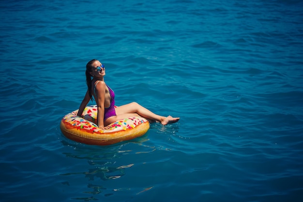 Mujer joven despreocupada disfrutando de un día relajante en el mar flotando en un anillo inflable vista superior Concepto de vacaciones en el mar