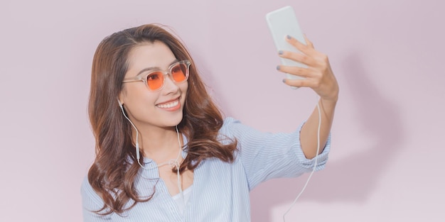 Mujer joven despreocupada escuchando con auriculares las pistas de su teléfono móvil