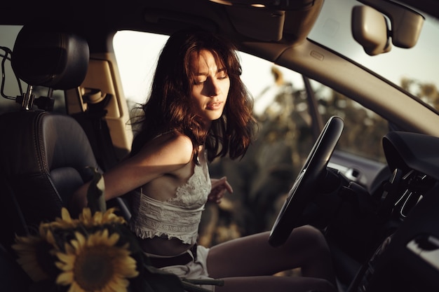 Mujer joven detuvo su coche en el campo de girasoles