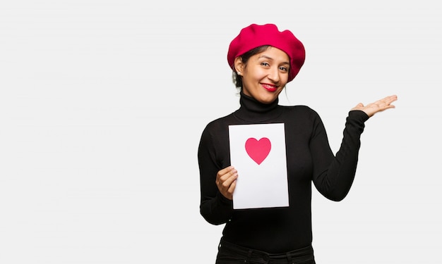 Mujer joven en el día de tarjetas del día de San Valentín que lleva a cabo algo con la mano