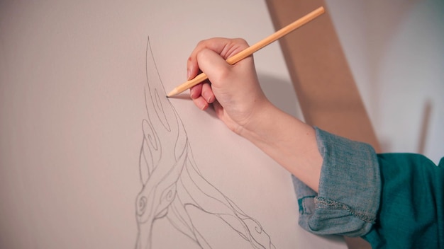 Una mujer joven dibujando un árbol abstracto en el lienzo con lápiz