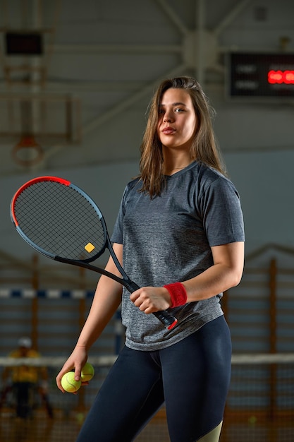 Mujer joven discapacitada en silla de ruedas jugando al tenis en la cancha de tenis