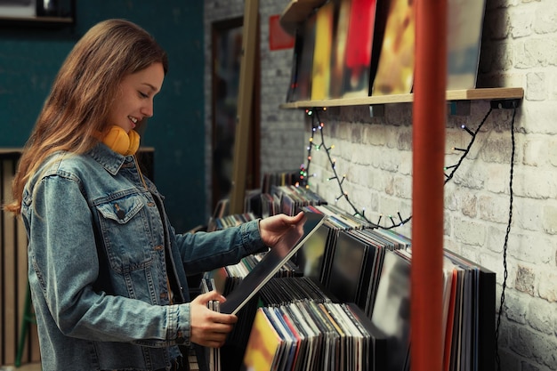 Mujer joven con disco de vinilo en la tienda