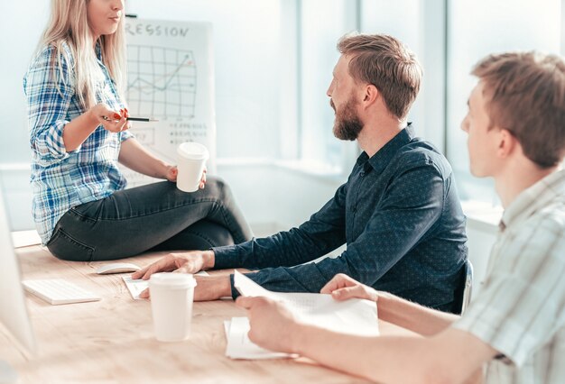 Mujer joven discutiendo con sus colegas nueva estrategia. el concepto de trabajo en equipo