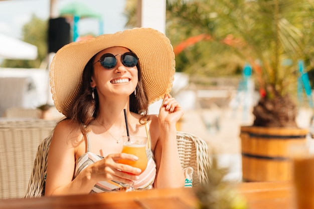 Mujer joven disfruta de un cóctel al aire libre en la playa.