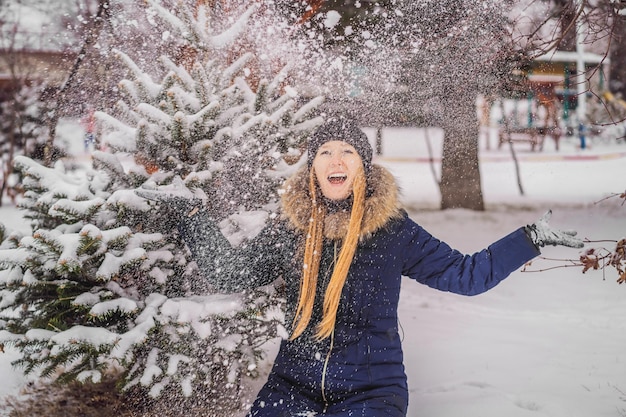 Mujer joven disfruta de un día de nieve de invierno en un bosque nevado