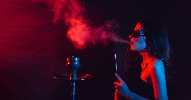 Mujer joven disfruta fumando una pipa de agua