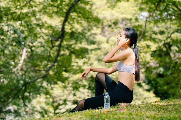 Mujer joven disfruta de la música y tiene las manos en los auriculares al aire libre.