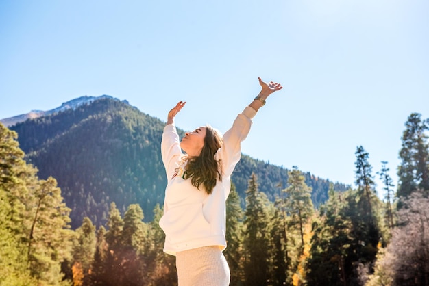 Mujer joven disfrutando de la belleza de la naturaleza de un río de montaña Chica turista en las montañas