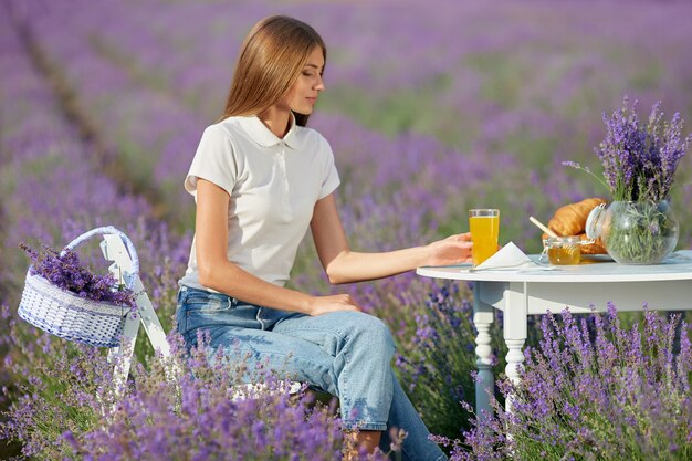 Mujer joven disfrutando de la cena en el campo de lavanda