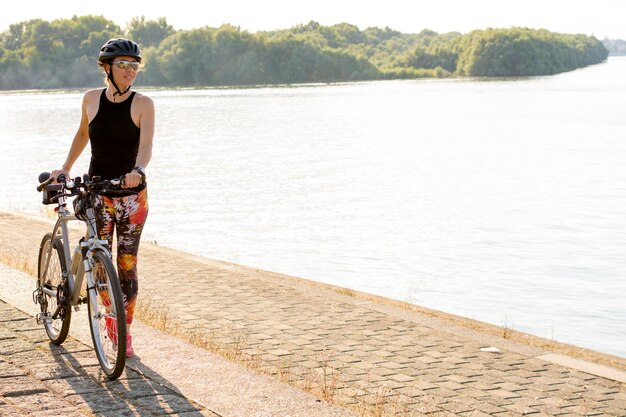 Mujer joven disfrutando de ciclismo cerca del río