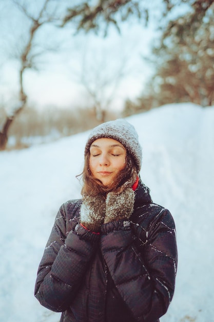 Mujer joven disfrutando del clima invernal en el bosque de nieve clima frío vacaciones de invierno