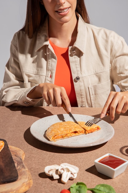 Foto mujer joven disfrutando de una deliciosa pizza calzone