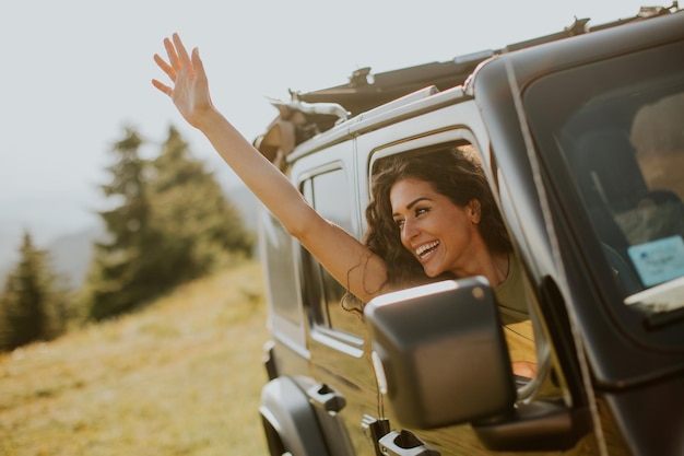 Mujer joven disfrutando de la libertad en un vehículo todoterreno en un día soleado