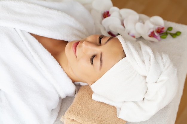 Mujer joven disfrutando de un masaje facial en el salón de spa.