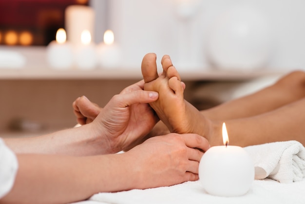 Foto mujer joven disfrutando de un masaje de pies en el salón de spa, se centran en las piernas