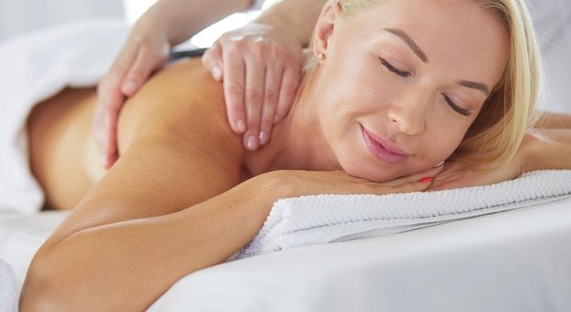 Mujer joven disfrutando de un masaje en el salón de spa