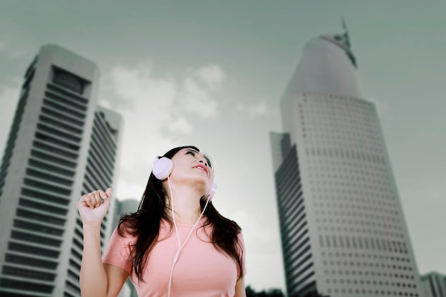 Mujer joven disfrutando de una música en la ciudad.