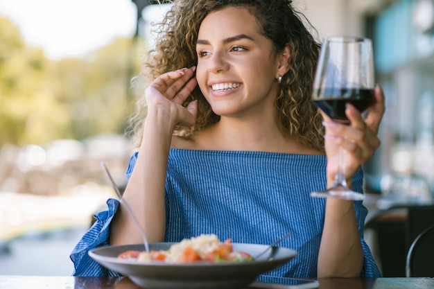 Foto mujer joven disfrutando y relajándose mientras almuerza en un restaurante.