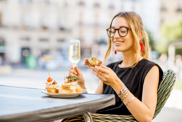 Mujer joven disfrutando de un sabroso aperitivo con pinchos, aperitivo tradicional español, con una copa de vino sentado al aire libre en el bar en la ciudad de Valencia